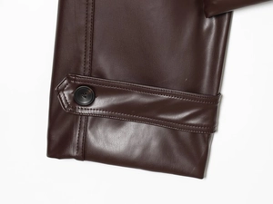 Detailed close-up of dark brown faux leather cuff with buttoned strap and fine stitching