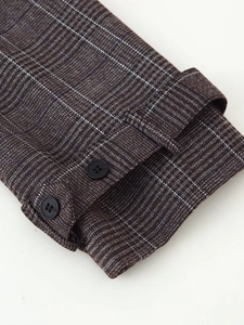 Close-up of winter plaid suit sleeve featuring decorative buttons and textured cuff detail