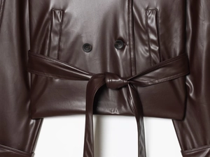Detail of dark brown leather trench coat featuring waist belt knot and black buttons