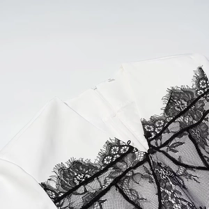 Detail of white dress featuring black eyelash lace trim and an invisible zipper back