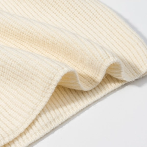 Dettaglio ravvicinato del tessuto a maglia a coste crema con texture morbida e qualità