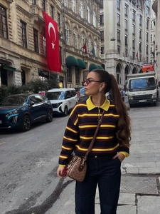 Close-up of polo collar knitwear with navy and burgundy stripes in a street style look
