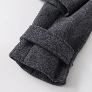 Detailed close-up of charcoal grey wool coat cuff with stylish decorative strap and premium stitching