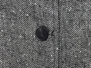 Macro shot of herringbone wool fabric texture and black four-hole resin button detail