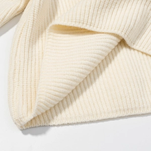 Dettaglio macro della maglia color crema con trama a coste verticali e orlo spesso