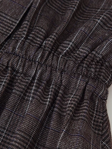 Close-up of brown plaid fabric texture and elastic waistband smocking on the garment