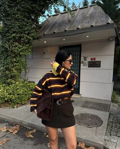 Detail of multi-color striped polo sweater in yellow, brown and navy with suede tote bag