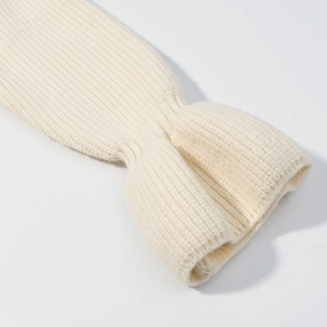 Dettaglio di polsini in maglia color crema con volant, trama a costine e design svasato
