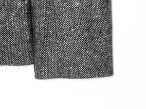 Close-up of black and white herringbone tweed fabric texture on women's slim blazer