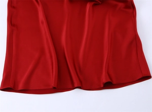 Detailed close-up of the smooth red satin fabric hemline with a silky finish and soft luster