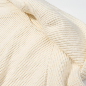 Dettaglio del maglione in maglia a coste color crema con texture in lana morbida