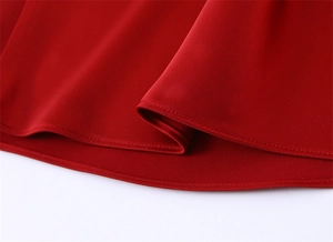 Detailed close-up of smooth red satin fabric with professional reinforced stitching