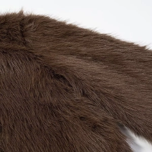 Gros plan sur la texture épaisse de fausse fourrure brun foncé sur un manteau d'hiver
