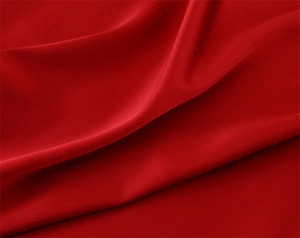 Detailed close-up of smooth red silk satin fabric with elegant drapes and soft texture