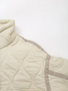 Detailed macro view of onion quilted pattern and grey tape trim on cream jacket