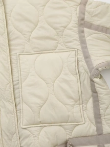 Detail of cream onion quilted jacket featuring a square pocket and contrast binding