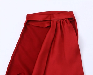 Macro detail of high-quality red satin fabric with elegant pleated texture and stitching