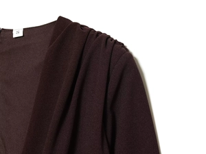 Détail macro d'une robe marron foncé avec plis élégants aux épaules et tissu texturé