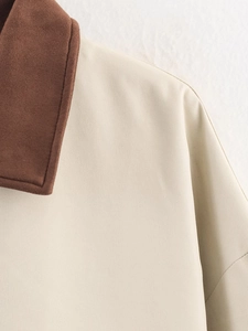 Detail view of the brown suede collar and beige twill fabric stitching on the jacket