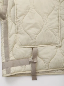 Close-up of quilted beige jacket showing gourd pattern stitching and contrast drawstrings