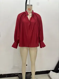 Detail of burgundy V-neck blouse featuring elegant pleated neckline and lantern sleeves