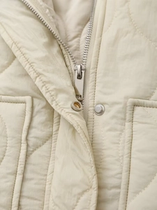 Detailed macro view of silver zipper and snap buttons on beige quilted winter jacket