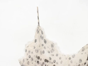 Détail d'une robe blanche à pois avec dentelle cils délicate et fines bretelles