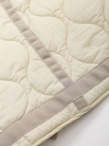 Macro view of wave-patterned quilted jacket with premium reinforced ribbon edging