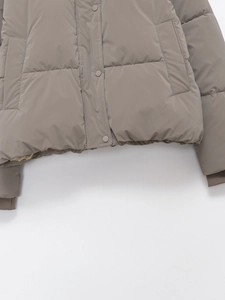 Detail view of khaki hooded puffer jacket with snap buttons and ribbed cuffs on quilted fabric