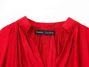 Detailed view of the red shirt V-neckline with pleated texture and brand size label