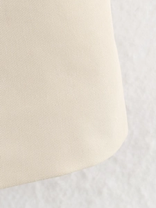 Close-up of beige twill fabric texture on winter trench coat showing premium material detail