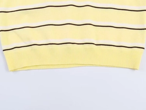 Detailed close-up of knit texture and striped hem on a yellow long sleeve polo sweater