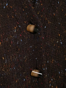 Detail of dark brown chunky knit sweater with colorful speckles and marble-effect button
