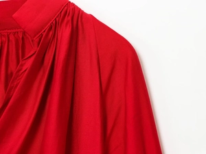 Detailed close-up of delicate pleats on a red V-neck shirt with smooth silk-like texture