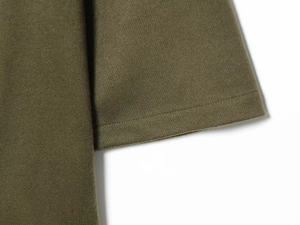 Detailed close-up of olive green knitted fabric showing twill texture and fine stitching