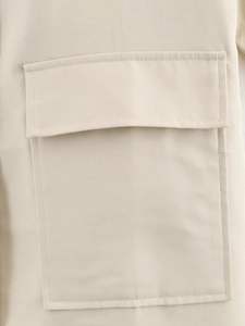 Detailed close-up of beige trench coat pocket with reinforced stitching and twill fabric