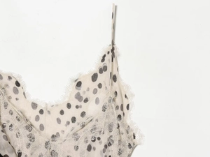 Détail de la dentelle délicate au décolleté et motif à pois noirs sur robe beige