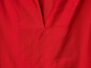 Close-up of V-neckline stitching and red fabric texture on long sleeve shirt