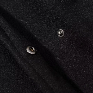 Detailed close-up of metallic silver snap buttons on black wool-like winter coat fabric