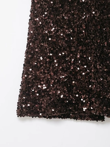 Detailed view of shimmering dark brown sequins on fishtail skirt fabric with metallic shine