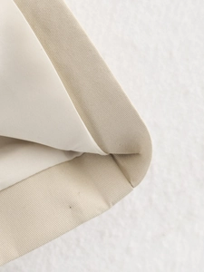 Detailed macro view showing beige cotton trench coat hem with fine twill texture and lining