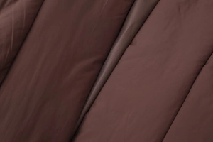 Close-up of matte dark brown quilted fabric texture with detailed stitching and soft padding