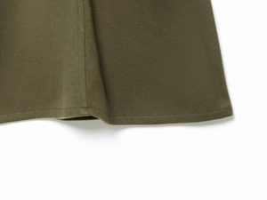 Detail of dark olive green knit dress hem with premium stitching and wool-like texture