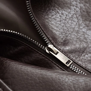 Detail of dark brown pebble grain PU leather jacket featuring a silver metal zipper
