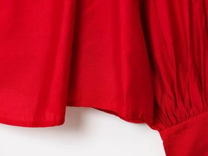 Detail of red long sleeve blouse featuring pleated cuffs and premium double stitching