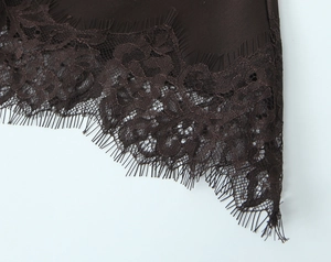 Detail of dark brown satin dress hem featuring delicate floral eyelash lace trim