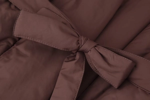 Close-up of brown quilted winter jacket featuring windproof fabric and a tied waist belt