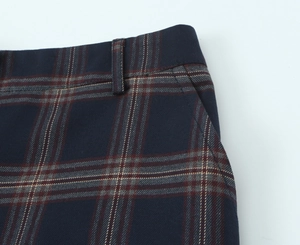 Macro detail of plaid trouser waist showing belt loops and navy checked fabric texture