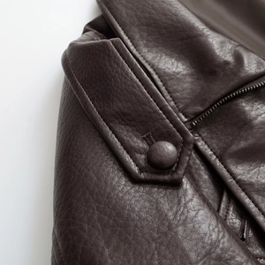 Close-up of vintage brown PU leather jacket featuring epaulets and metal zippers