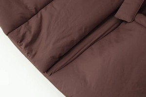 Detailed macro view of deep brown quilted jacket fabric and wide horizontal stitching